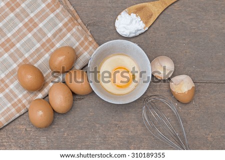 Eggs,wooden spoon,whisk on wooden background,kitchen concept