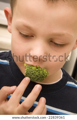 A young child puts a piece of broccoli in his mouth