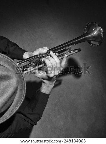 Over head black & white image of man in fedora playing trumpet.