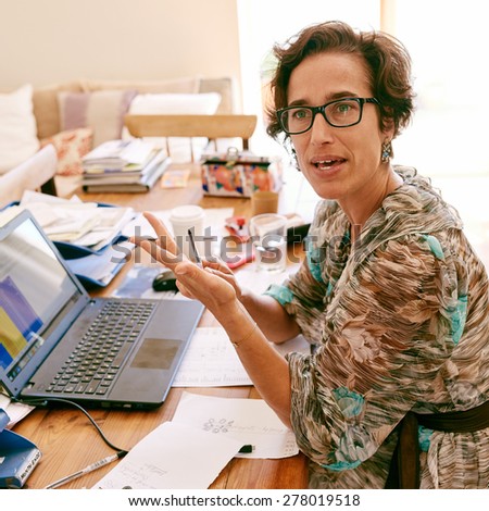 Square image of a strong entrepreneurial business woman wearing glasses, using her hands to make gestures while speaking to someone off camera in a confident manner