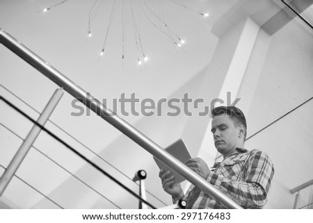 Black and white image of a successful young professional business man busy using his tablet to go online to do his banking