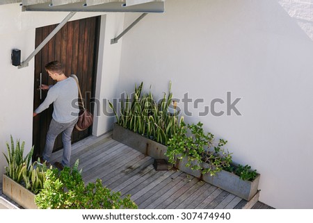 Young successful business man busy locking his front door after arriving at his beach house