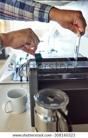Close up of a man\'s hands busy inserting a coffee pod into coffee machine to make his morning cup of espresso