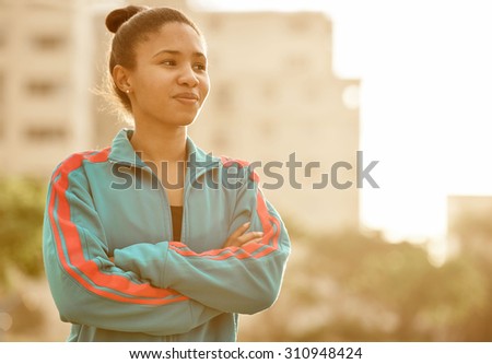 Confident young female runner looking off to the side as she slightly smiles with flare pouring from the side of the frame