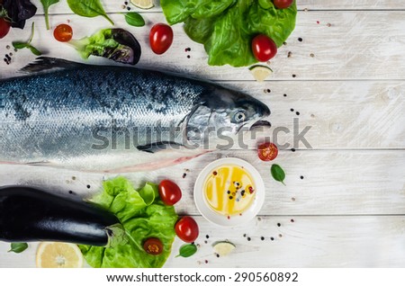 Top view of whole Atlantic salmon with aromatic herbs, spices and lemon. Top view seafood photo with place for your text. Vegetarian or paleo food concept.