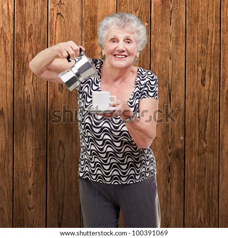 portrait of a vitality senior woman serving a cup of tea against a wooden wall