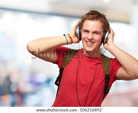 portrait of a cheerful young student listening to music with headphones indoor