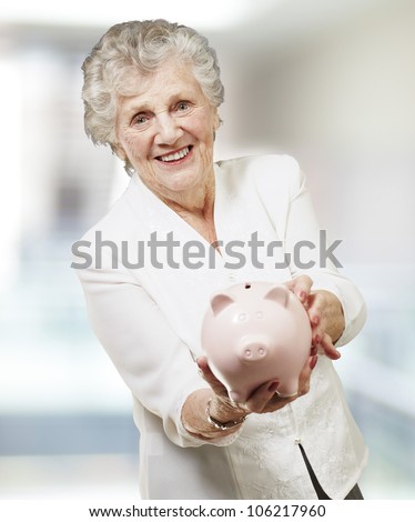portrait of a senior woman showing a piggy bank, indoor