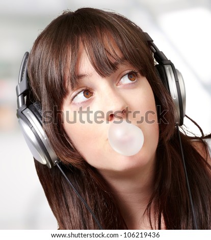 portrait of a young woman listening to music with bubble gum indoor