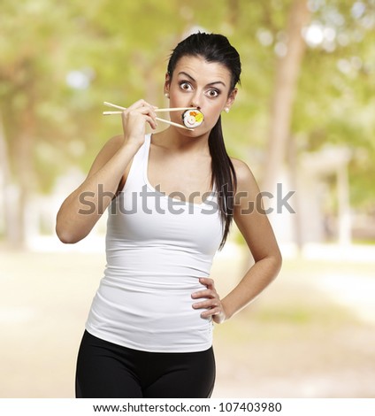 young pretty woman eating sushi against a nature background