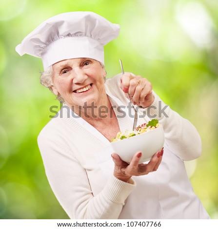 portrait of an adorable senior cook woman eating a salad against a nature background