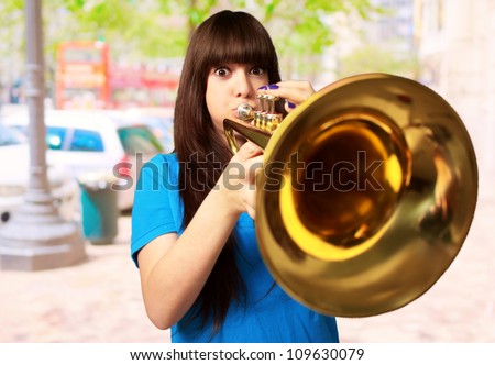 portrait of a young girl blowing trumpet, outdoor