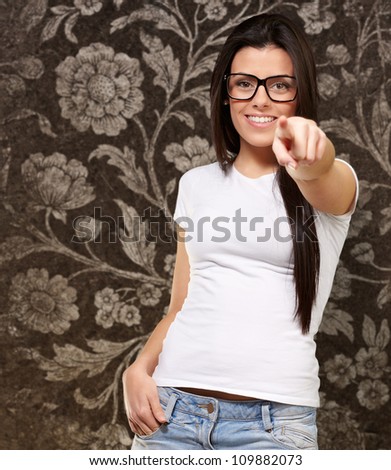 portrait of a young woman pointing with her finger against a grunge wall