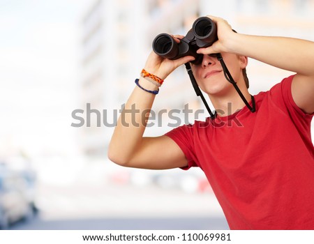 portrait of young man with binoculars against a building