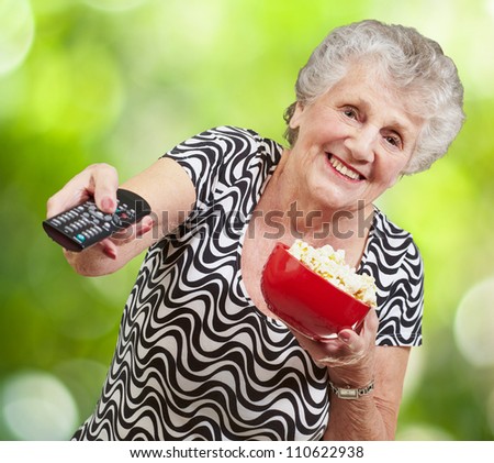 portrait of happy senior woman looking the tv against a nature background