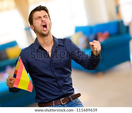 Man cheering and holding flag, indoor