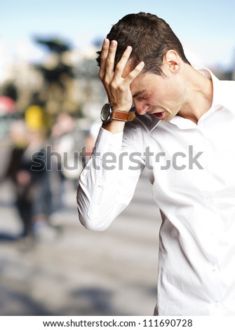 Angry young man doing frustration gesture at crowded place