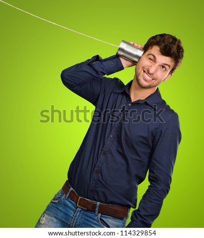 Man Listening From Tin Can Telephone against a green background
