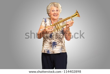 Portrait Of A Senior Woman Holding A Trumpet On gray Background