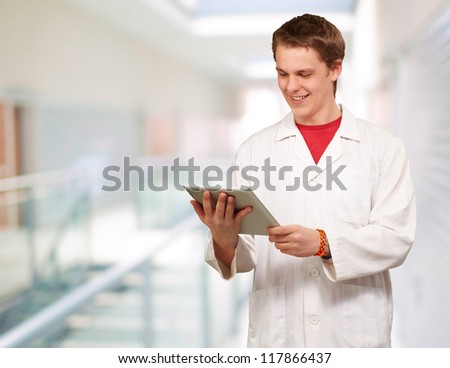 portrait of young academic holding a digital tablet at entrance of modern building