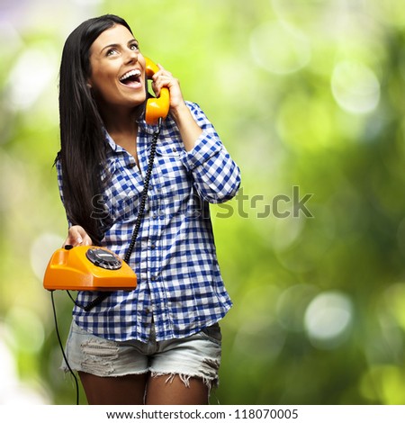 portrait of young woman talking on vintage telephone against a nature background