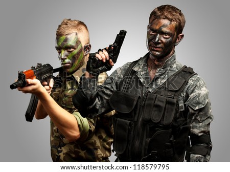 Portrait Of Young Soldier With Gun And Jungle Camouflage Paint On A White Background