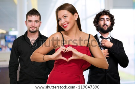 Woman Standing In Front Of Men Making A Heart Shape Sign, Indoor