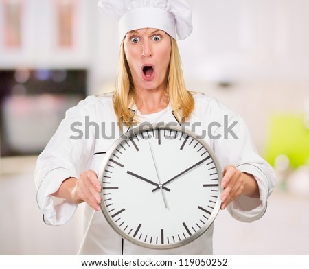 Shocked Female Chef Holding Clock in a kitchen, indoor