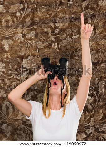 woman looking through binoculars and pointing up against a vintage background