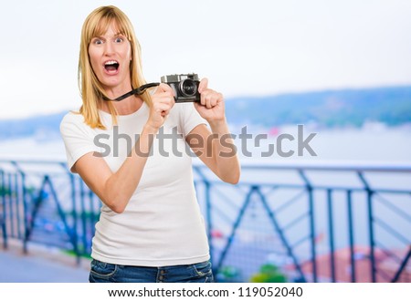 Shocked Woman With Old Camera standing near the shore