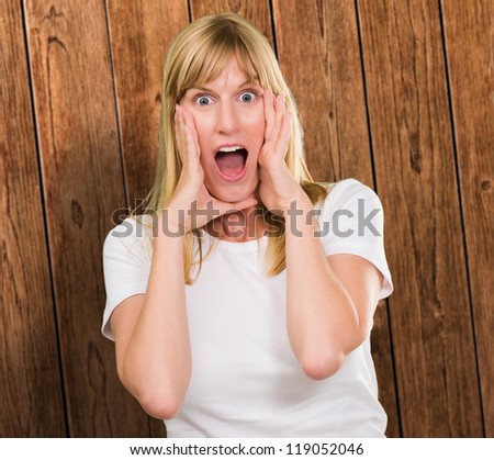 Portrait Of Shocked Woman against a wooden wall background