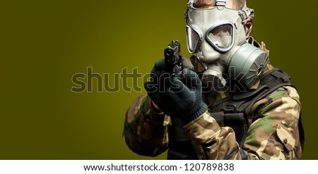 Portrait Of A Soldier With Gas Mask Aiming With Gun against a dark green background