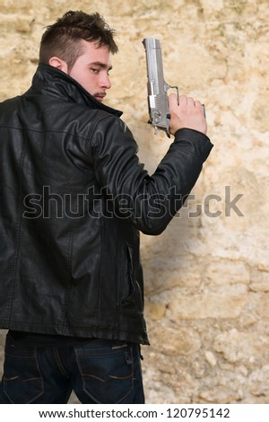 Portrait Of A Man Holding Gun against a stone background