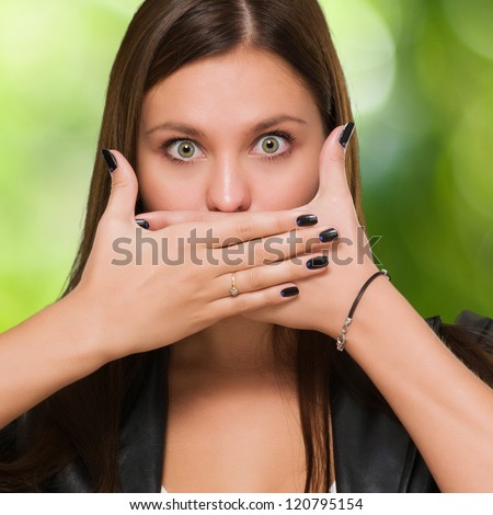 Shocked woman covering her mouth against a nature background