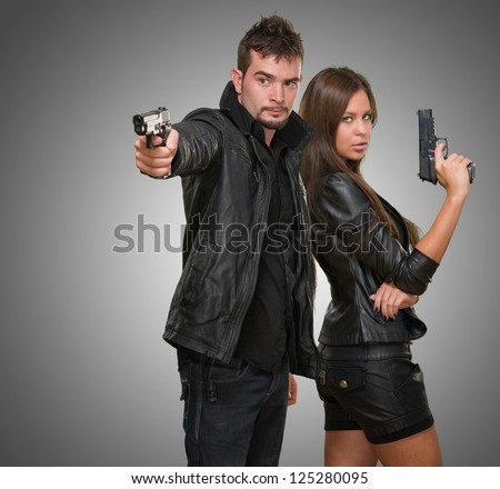 Portrait of a couple holding guns against a grey background
