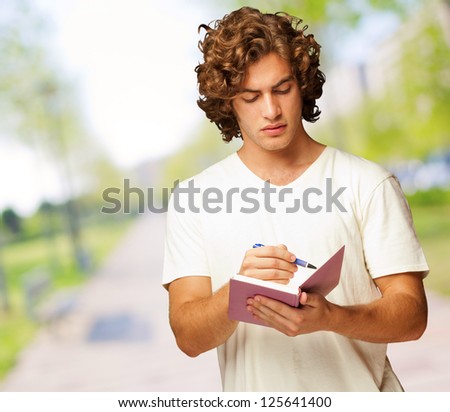 A Young Man Writing On A Notebook, Outdoor