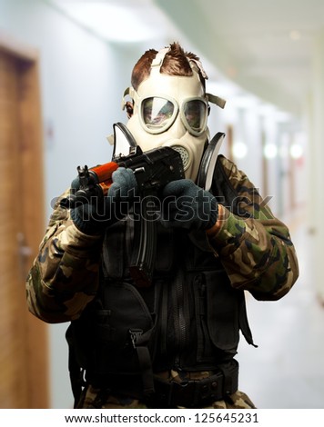 Portrait Of A Soldier With Gas Mask Aiming With Gun in a passage way