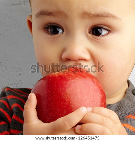 Portrait Of Baby Boy Eating Red Apple against a grunge background