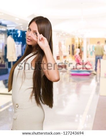 Beautiful Smiling Woman Showing Two Fingers In Front Of Eye in a luxury shop