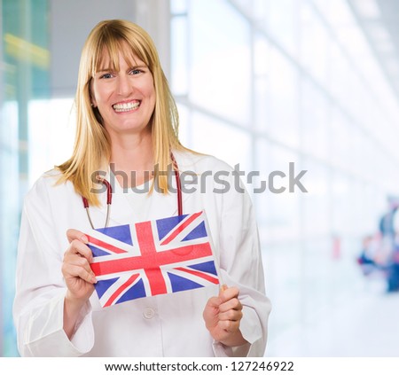 Happy Doctor Holding British Flag against an abstract background, indoor
