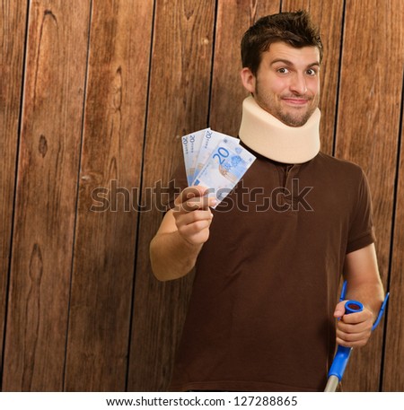 Disabled Man With Neck Brace Holding Euro Note On Wooden Background