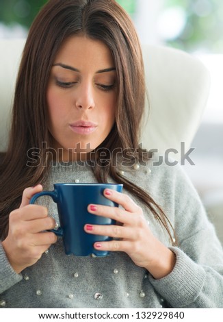 Woman Blowing In Coffee Mug, Indoors