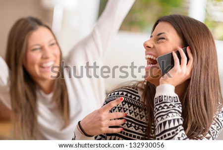 Young Women Talking On Cell Phone And Laughing, Indoors