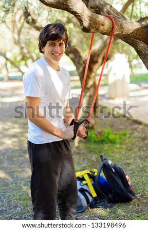 Young Man Exercising With Stretch Band; Outdoors