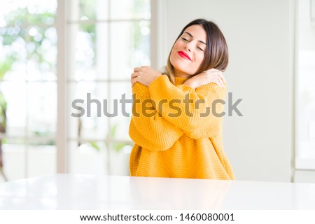 Young beautiful woman wearing winter sweater at home Hugging oneself happy and positive, smiling confident. Self love and self care Сток-фото © 