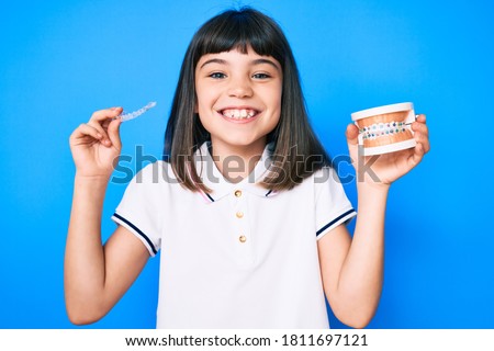 Young little girl with bang holding invisible aligner orthodontic and braces smiling with a happy and cool smile on face. showing teeth.  Stock foto © 