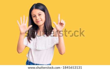 Beautiful child girl wearing casual clothes showing and pointing up with fingers number seven while smiling confident and happy. 