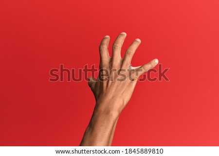 Hand of hispanic man over red isolated background grasping aggressive and scary with fingers, violence and frustration  商業照片 © 