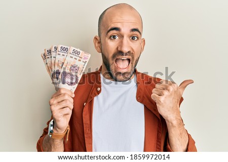 Hispanic bald man holding 500 mexican pesos banknotes screaming proud, celebrating victory and success very excited with raised arm  Foto stock © 