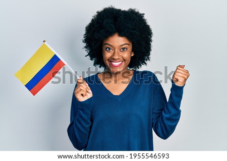 Young african american woman holding colombia flag screaming proud, celebrating victory and success very excited with raised arm  Foto stock © 